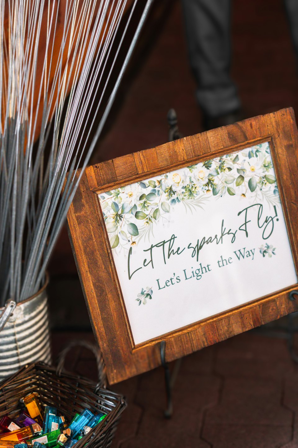 Event sign with sparklers and lighters on brick flooring.