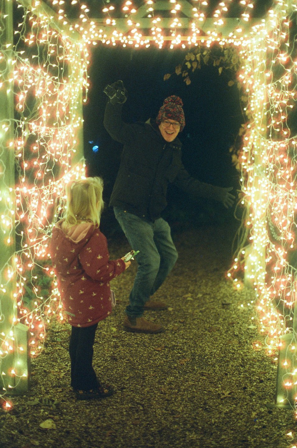 An adult and child interact under an illuminated archway.